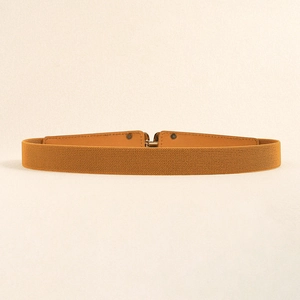 Detail view of ginger yellow elastic waist belt with leather accents and metal buckle