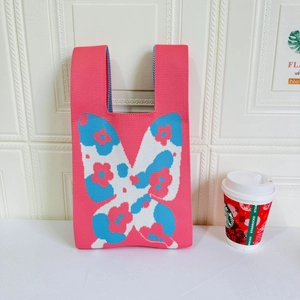 Close-up of pink knit tote bag with large floral butterfly pattern and wide straps