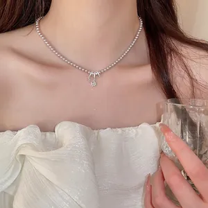 Collier de perles élégant avec pendentif nœud argenté et zircon sur mannequin