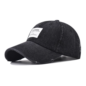 Detail of washed black denim baseball cap showing distressed brim and vintage patch