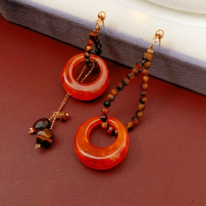 Macro shot of resin tiger eye earrings with brown beads and metal chain tassel detail