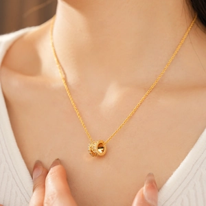 Close-up of 18k gold plated necklace with cylinder zircon pendant on a female model