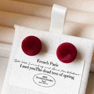Gros plan de boucles d'oreilles rondes en velours rouge sur une carte à bijoux blanche
