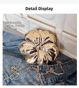 Detailed macro view of the gold flower-shaped evening clutch with textured petals and chain