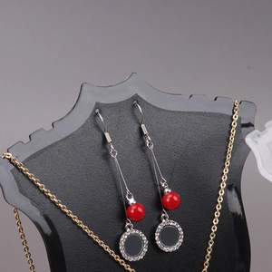 Red beaded drop earrings with black rhinestone pendants on a professional display stand