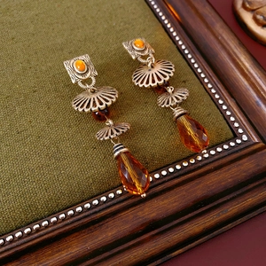 Macro shot of vintage bronze water-drop earrings with amber gemstones on green fabric