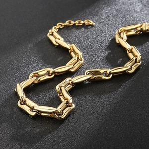Close-up of golden chunky coffee bean chain necklace on a black textured background