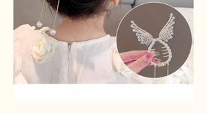Détail d'une pince à cheveux ailes d'ange avec strass, perles et glands sur queue de cheval
