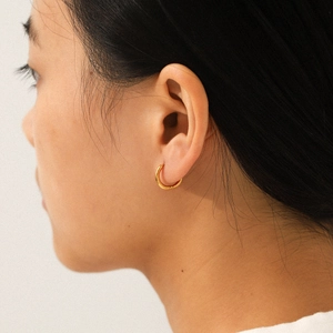 Close-up of minimalist 18K gold-plated stainless steel hoop earrings worn on a model