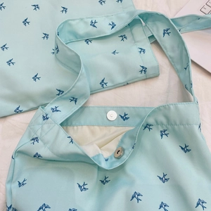 Detail of mint green canvas tote bag featuring swallow print and magnetic snap closure