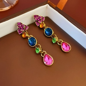 Close-up of vintage gold earrings with colorful crystals in a brown jewelry box