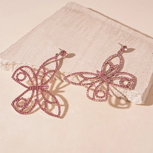 Detailed view of pink sparkling butterfly earrings with zirconia on a textured stone