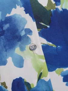 Détail macro d'une chemise en satin avec motif floral abstrait et bouton gris poli