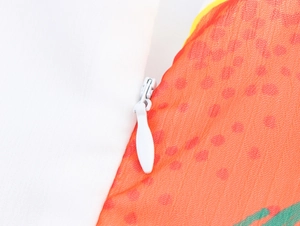 Gros plan d'une fermeture éclair invisible blanche sur un tissu textile imprimé orange