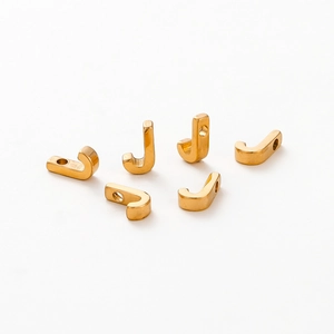 Macro shot of 6 polished gold-plated J-shaped alphabet beads for DIY jewelry making