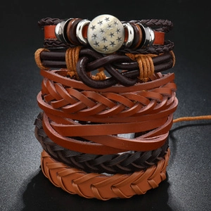 Detail of multi-layered brown leather braided bracelets with metal star charms on black background