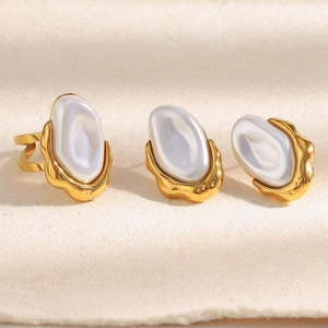 Detailed macro of 18K gold plated Baroque pearl earrings and open ring with lava texture