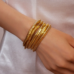 Close-up of gold layered bangles with fine horizontal texture on female wrist