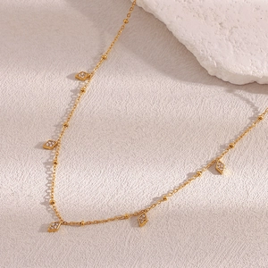 Detail of 18K gold-plated beaded chain featuring sparkling diamond-set rhombus pendants