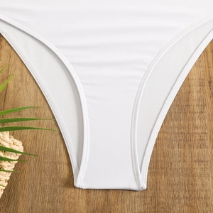 Detailaufnahme einer weißen gerippten Bikinihose auf einem strukturierten Holzhintergrund