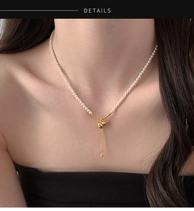 Détail d'un collier de perles avec pendentif gourde dorée et pompon élégant sur mannequin
