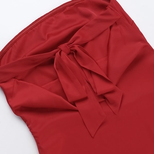 Detail of red satin dress featuring a large elegant bow tie and smooth silk texture