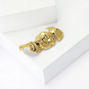 Macro shot of a vintage golden alloy mask brooch with abstract face texture and detail