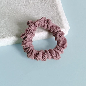 Gros plan détaillé sur la texture du chouchou en velours côtelé rose morandi