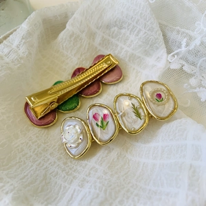 Detail of vintage French flower hair clips with golden edges on white lace fabric