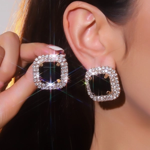 Elegant gold earrings featuring black square stones with sparkling rhinestone borders