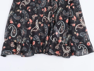 Close-up of black paisley print chiffon maxi dress featuring layered ruffle hem details
