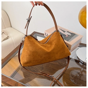 Detailed view of brown suede shoulder bag with silver zipper and leather strap texture