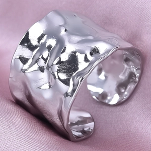 Macro detail of hammered texture and wavy edges on wide stainless steel open ring