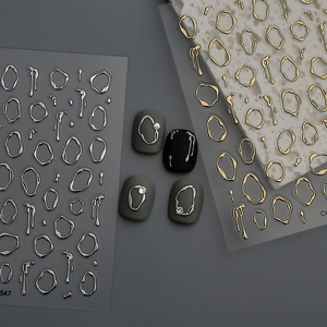 Detail of 3D metallic nail stickers featuring irregular gold and silver liquid shapes