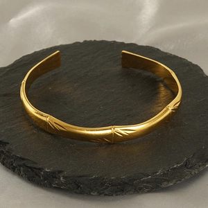 Bracelet jonc ouvert réglable en acier doré motif bambou sur socle en ardoise
