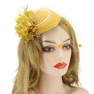Detail of yellow fascinator pillbox hat with mesh veil floral lace and pearl accents