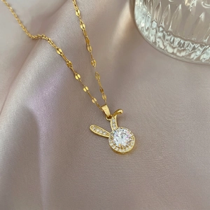 Charming golden rabbit pendant necklace with sparkling zircons on elegant silk fabric