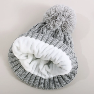 Close-up of gray knit winter hat showing thick white fleece lining and soft pompom