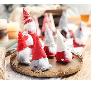 Close-up of red and grey Christmas gnomes on a metal tray with warm candlelight