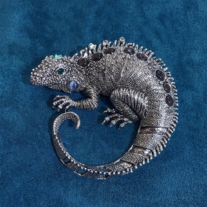 Artistic silver lizard brooch with multi-color gemstones and crystals on blue velvet