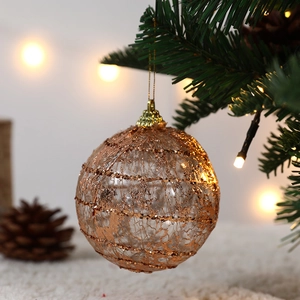Champagne gold hollow Christmas ball ornament hanging on tree with warm festive lights