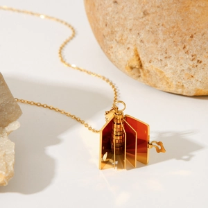 Polished gold book locket necklace featuring openable metal pages on a stone base