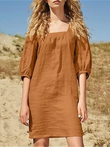 Detail of square neckline and puff sleeves on a linen dress against desert sand dunes