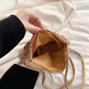 Handwoven straw crossbody bag with floral cutout design and secure zipper closure for beach