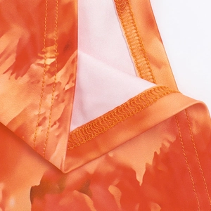 Detailed close-up of orange gradient print fabric and fine stitching on the strapless dress