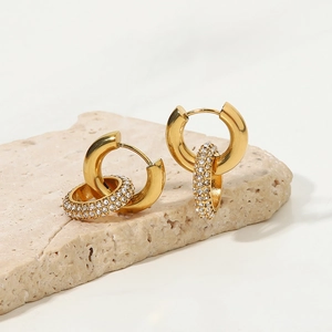 Detail of gold hoop earrings with detachable rhinestone rings on a stone display
