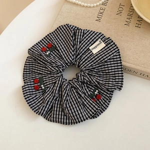 Détail d'un chouchou en tissu à carreaux avec cerises rouges et étiquette Happiness