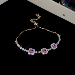 Adjustable gold bracelet with square pink crystals and diamond accents on black background