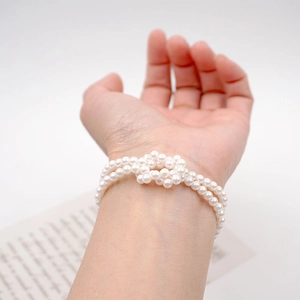 Elegant double-layered pearl strand bracelet featuring minimalist knot design on wrist