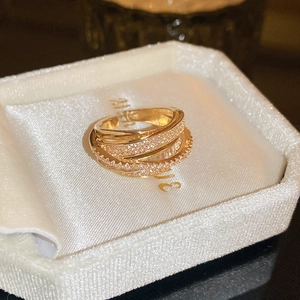 Close-up of multi-layer crisscross gold ring with pavé zircons in a jewelry box